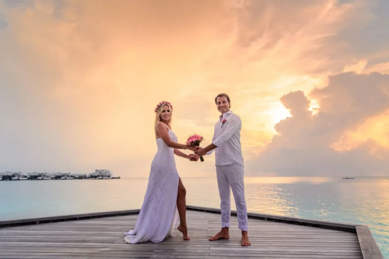 Un couple de jeunes mariés sur un ponton face aux karsts d'Asie du Sud-Est au coucher du soleil